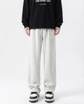 A tall man wearing white cotton straight leg sweatpants, front view full length
