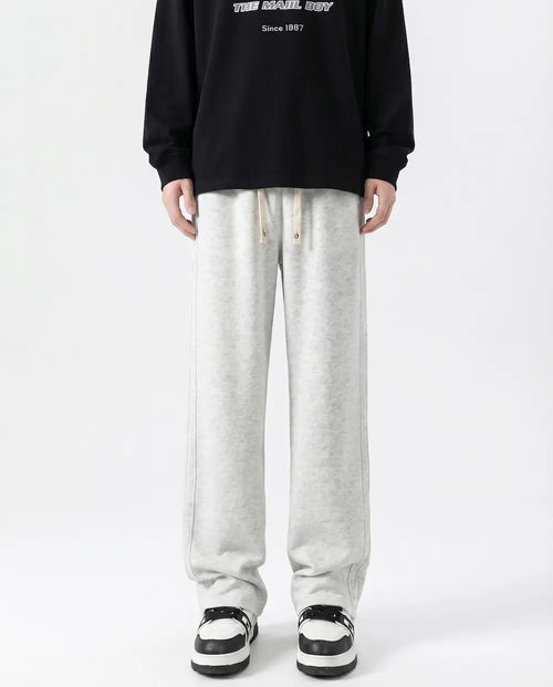 A tall man wearing white cotton straight leg sweatpants, front view full length