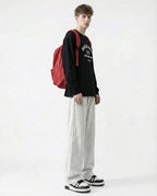 Tall man wearing white sweatpants with red backpack, side view full outfit