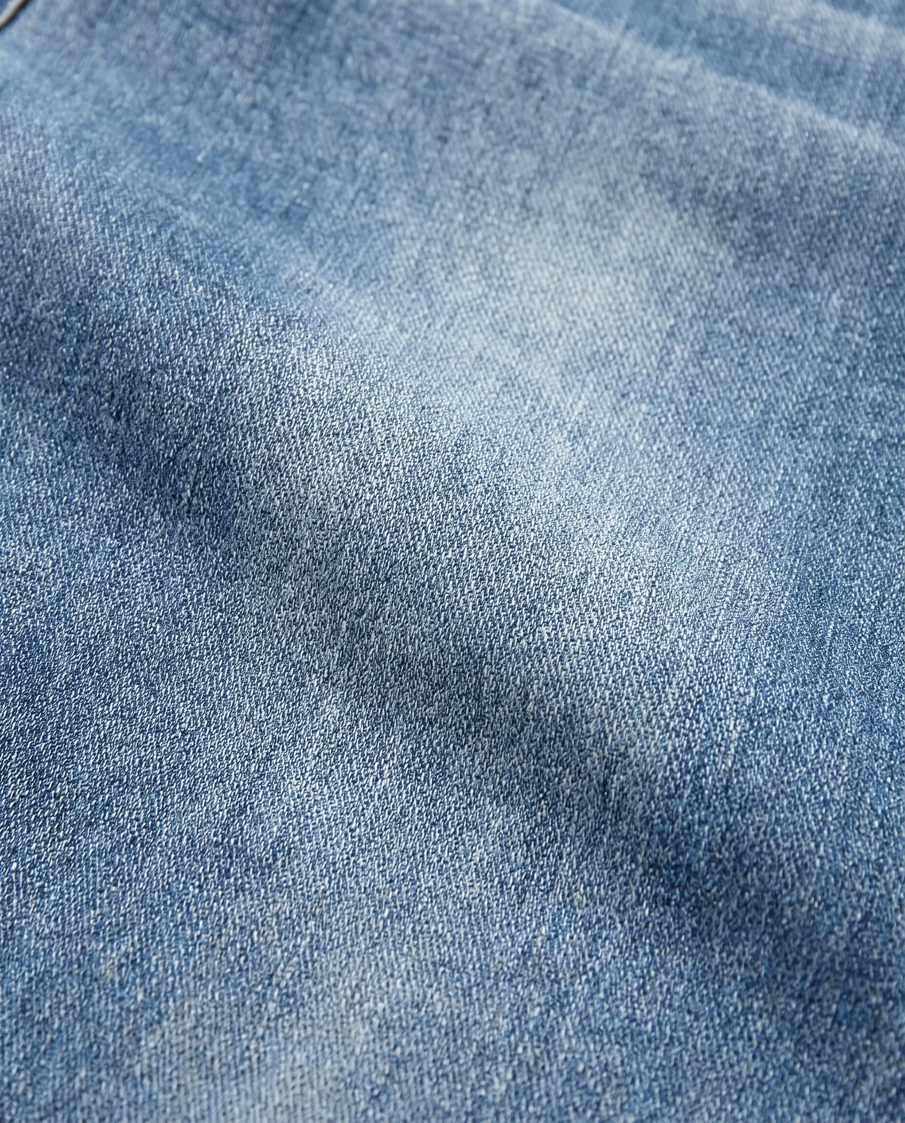 Light blue denim fabric texture detail of relaxed fit jeans