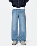A tall man wearing light blue relaxed fit jeans, standing front-facing