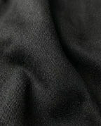 Close-up detail of black mid rise flare jeans for tall men, denim fabric texture and finish