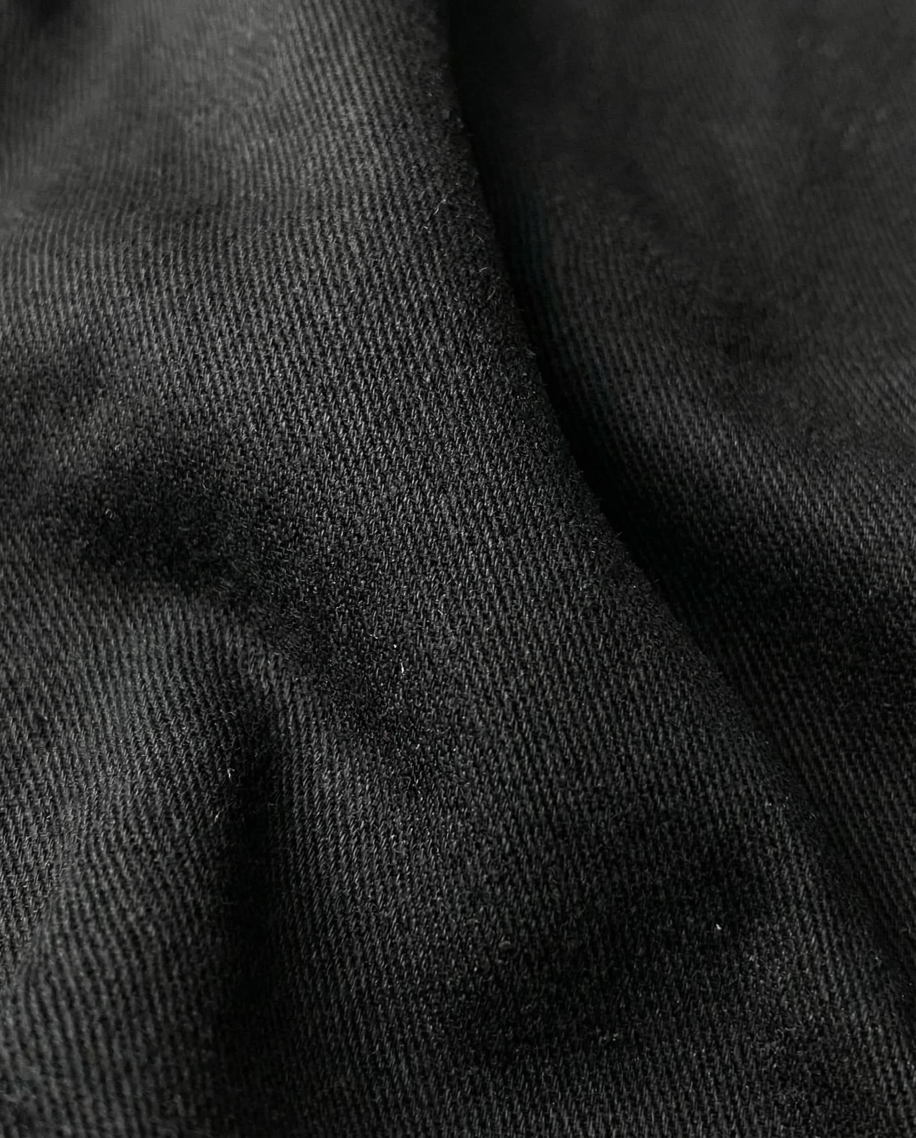 Close-up detail of black mid rise flare jeans for tall men, denim fabric texture and finish