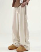 Cream pleated wide leg pants for tall men, full-length side view styled with brown chunky shoes