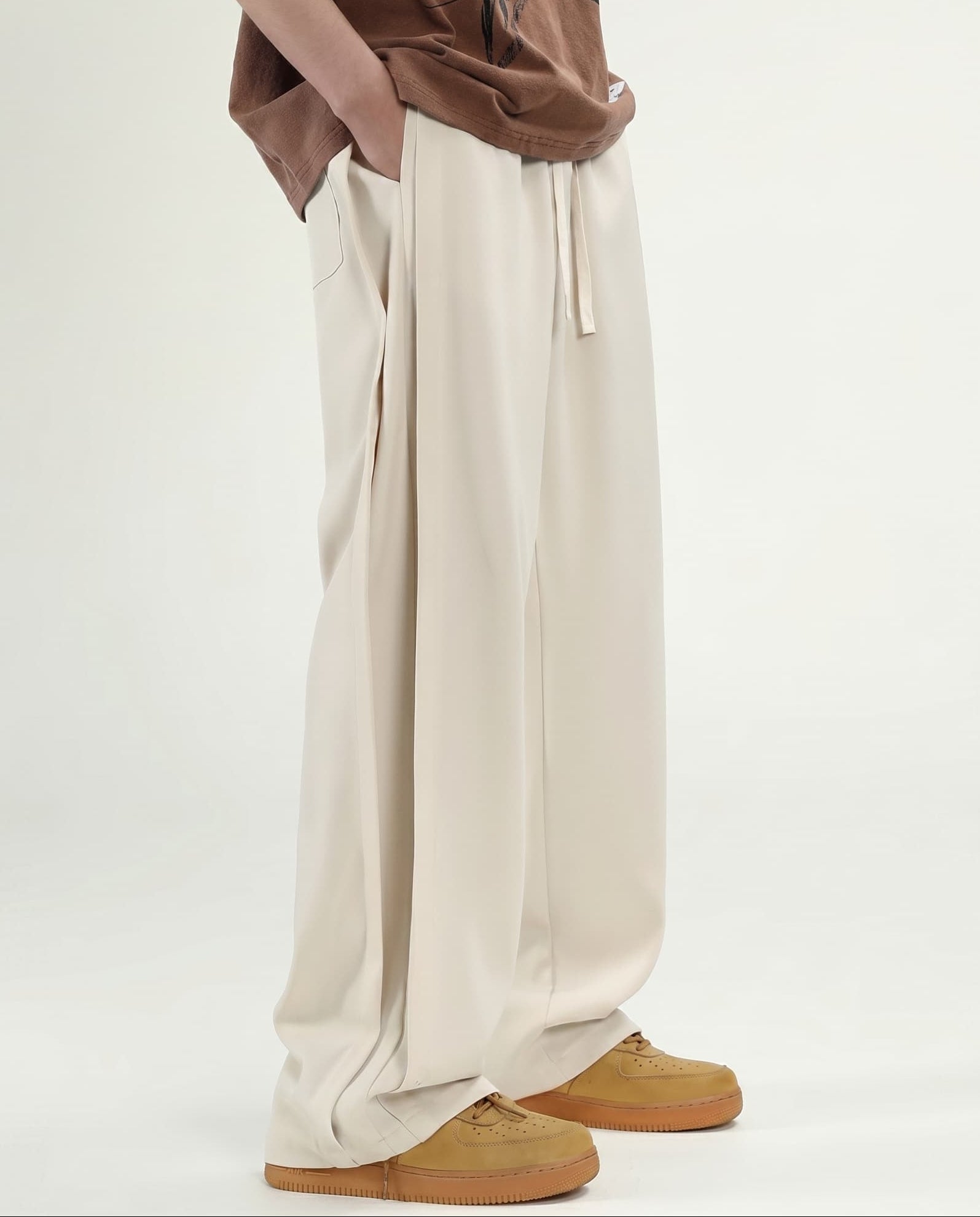 Tall men's cream pleated wide leg pants, front view highlighting pleat detail and relaxed wide silhouette