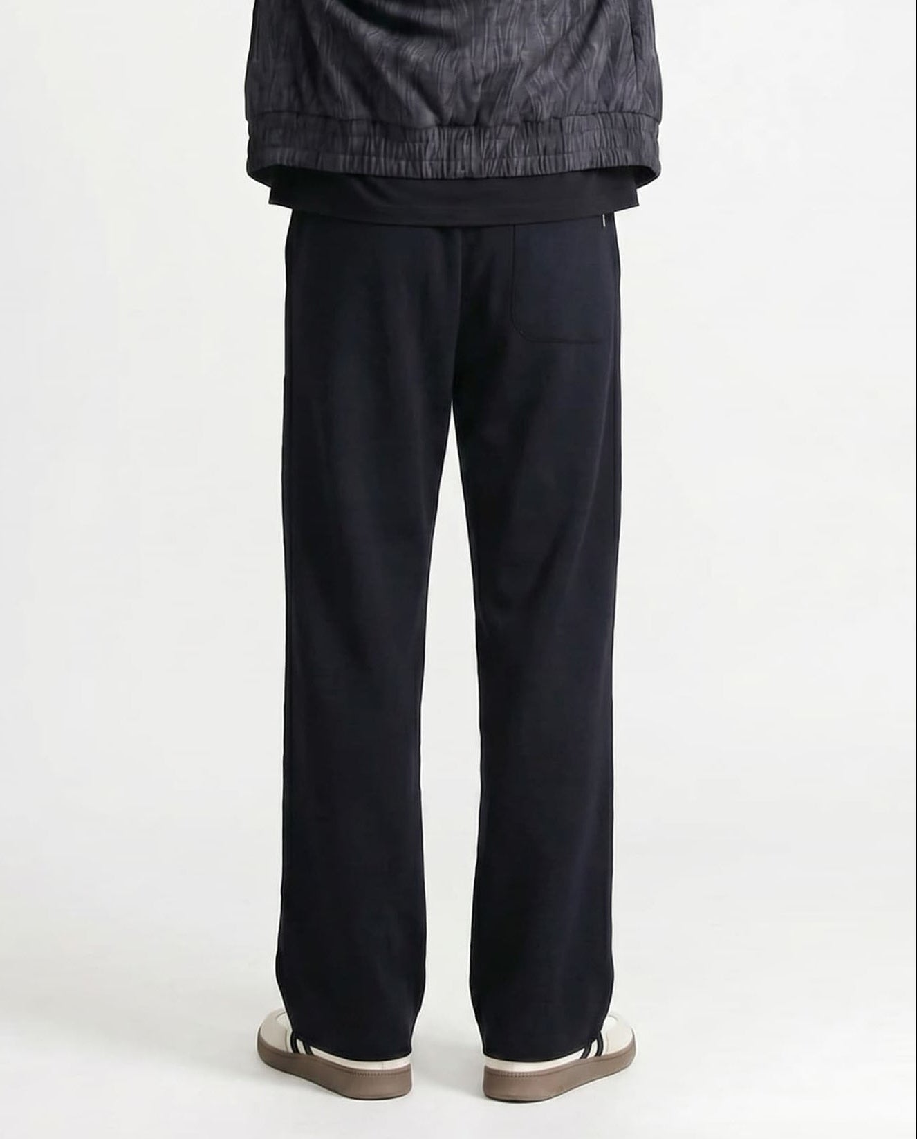 Tall men's black straight leg sweatpants, back profile highlighting straight cut and fabric drape