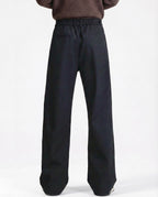 Men's black pleated trousers for tall men, back profile showing relaxed fit and fabric drape