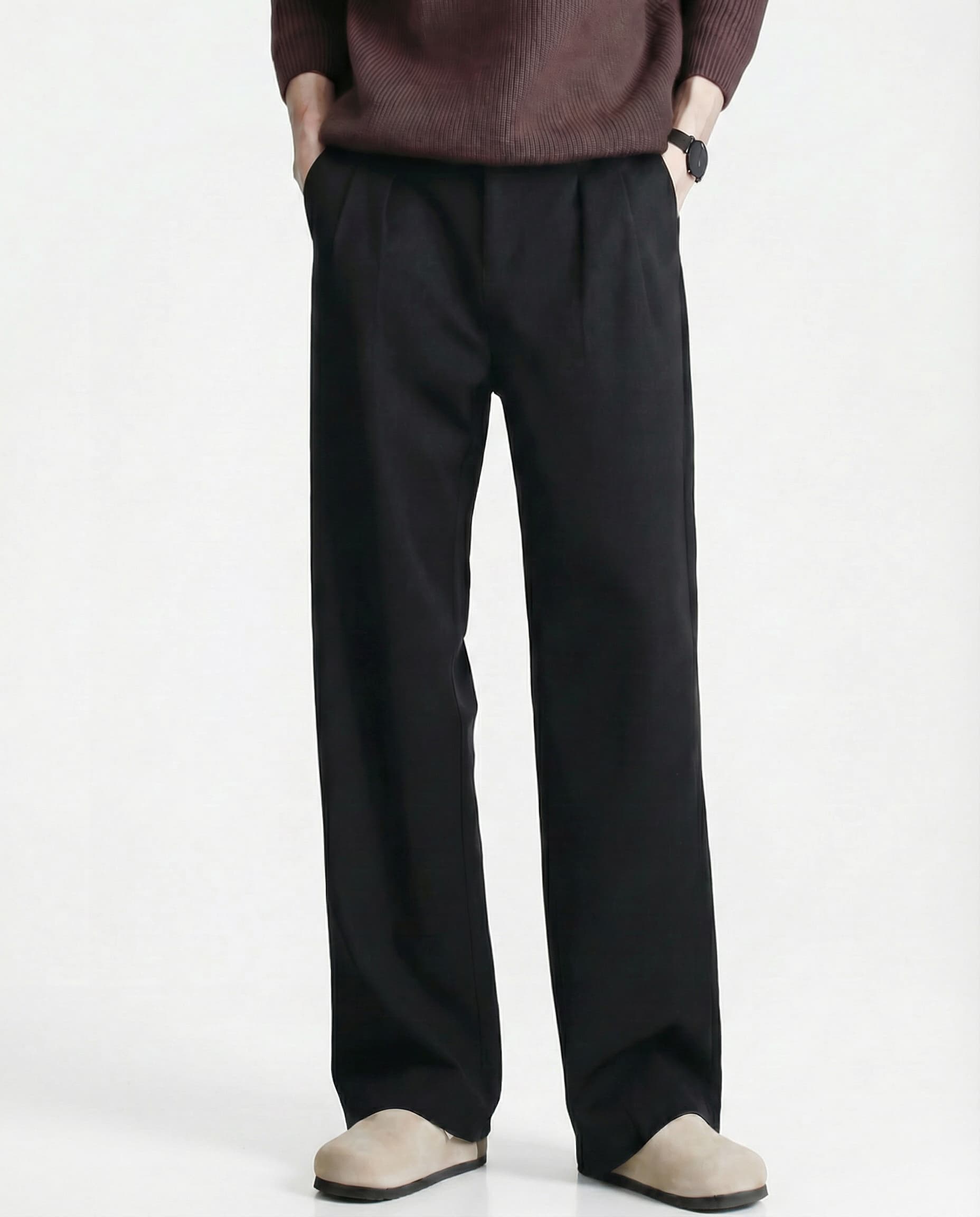Tall men's black relaxed pleated trousers, front view highlighting pleat detail and straight silhouette