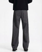 Tall men's gray pleated trousers, back view showing waistband and relaxed wide-leg silhouette