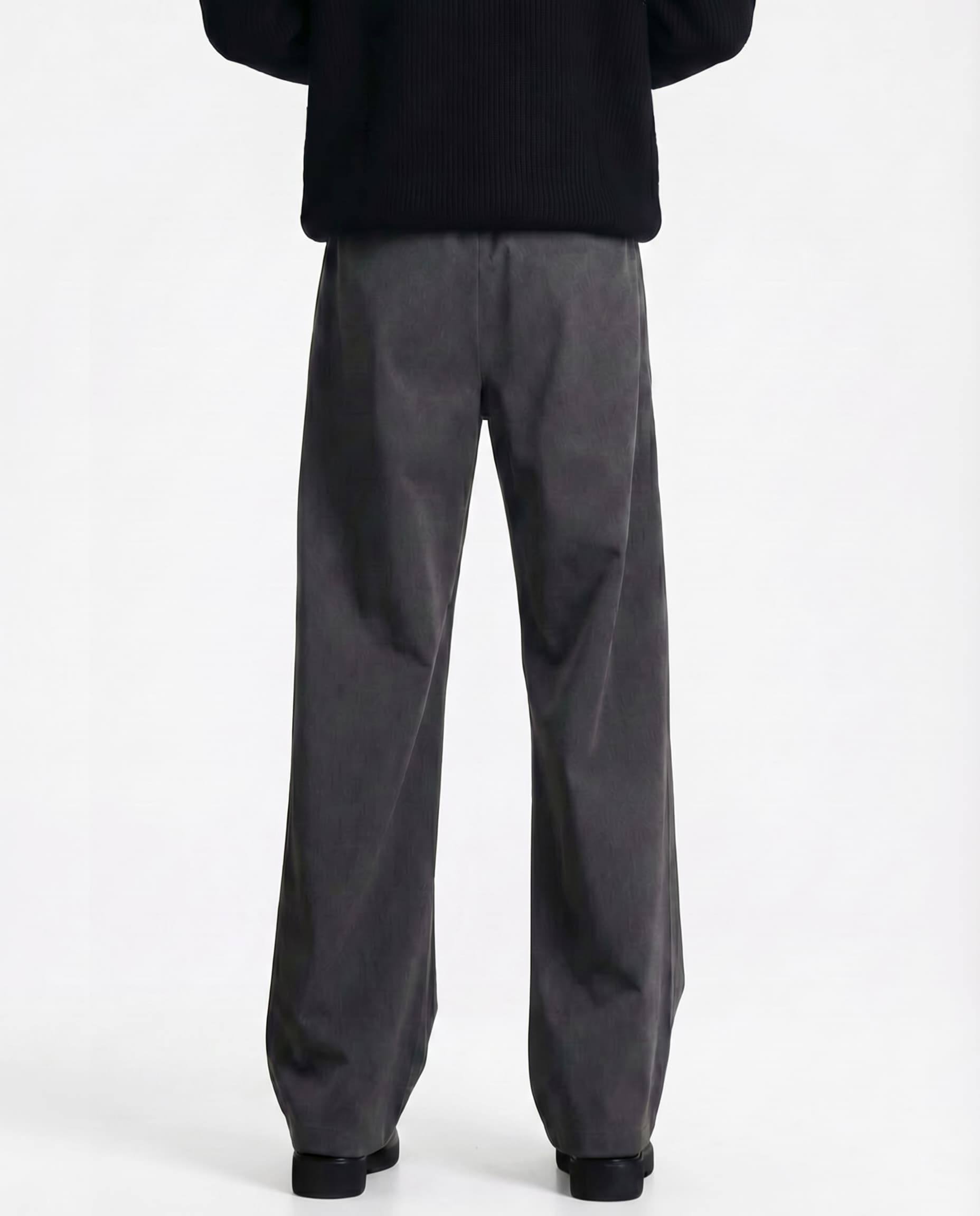 Tall men's gray pleated trousers, back view showing waistband and relaxed wide-leg silhouette